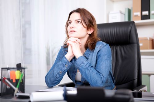 person in an office setting with hands clasped 