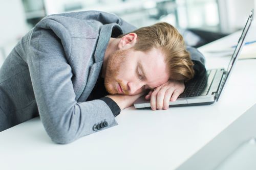 person asleep with head on laptop